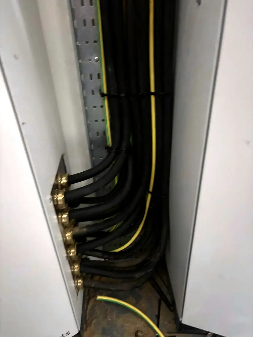 Cable entry glands at the base of a panel