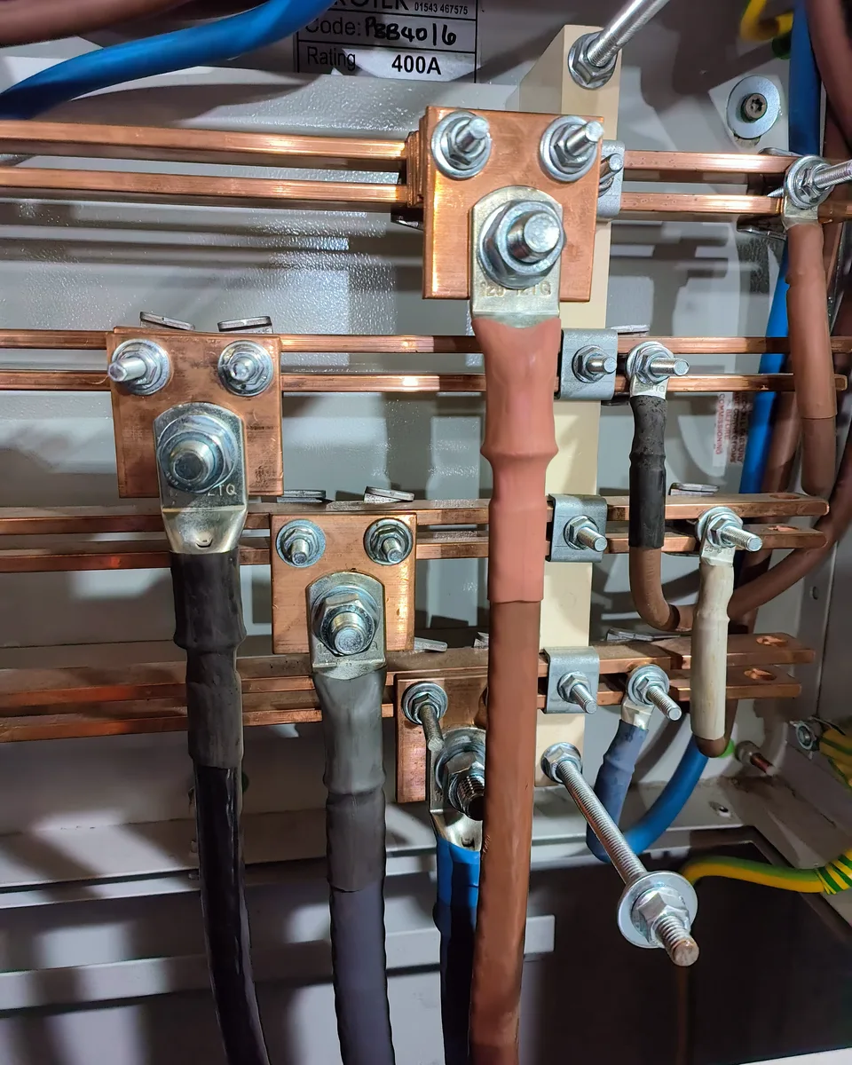 Cables lugged and bolted to copper busbars, with heat-shrink phase colours