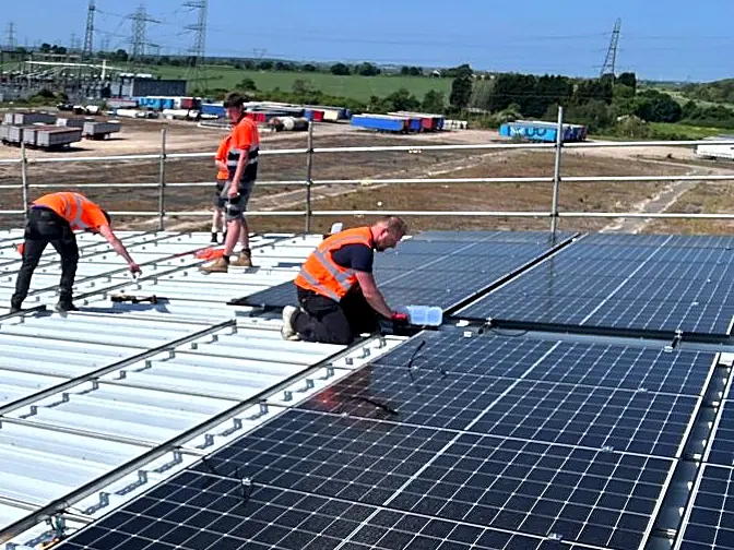 Solar PV installers fitting modules on a commercial metal roof