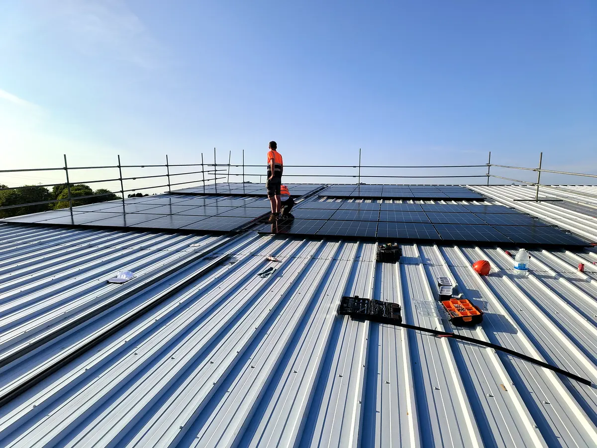 Module rows going in on a trapezoidal metal roof
